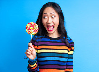 Hungry funny woman want to eat delicious colorful lollipop isolated  on blue background