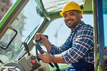 An engineer in uniform drives a green tractor.