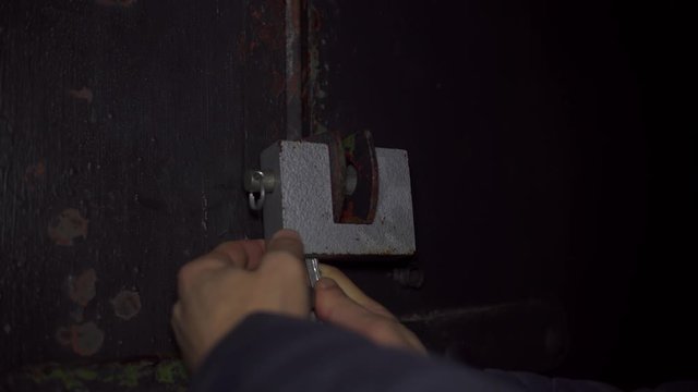 Men's hands block the unlocking of the old castle at the gate, the police arrive, emergency lights illuminate in red and blue.