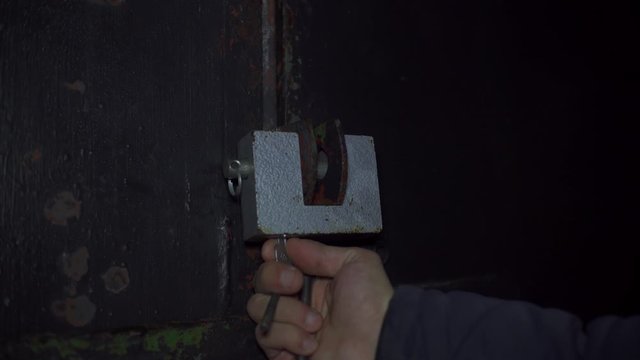 Men's hands block the unlocking of the old castle at the gate, the police arrive, emergency lights illuminate in red and blue.