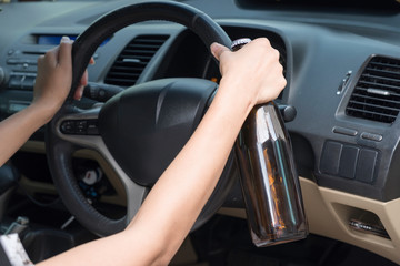 Fototapeta na wymiar Female Driving Car Holding Alcoholic Bottle.