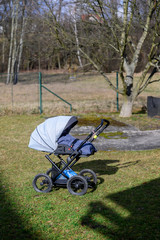 Baby carriage with sleeping baby outside in the garden.