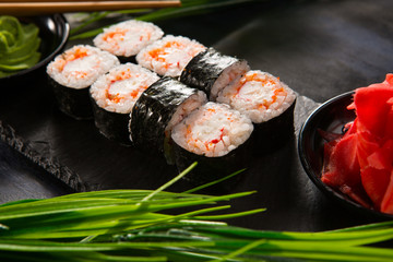 Set of sushi rolls with wasabi and ginger on a black background. Japanese oriental cuisine