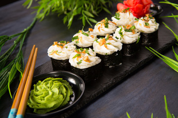 Set of sushi rolls with wasabi and ginger on a black background. Japanese oriental cuisine