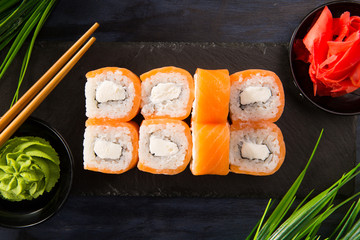 Set of sushi rolls with wasabi and ginger on a black background. Japanese oriental cuisine