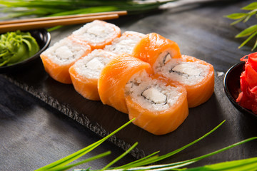 Set of sushi rolls with wasabi and ginger on a black background. Japanese oriental cuisine