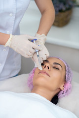 Cosmetologist wearing gloves doing mesotherapy for patient
