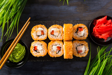 Set of fried sushi rolls with wasabi and ginger on a black background. Japanese oriental cuisine