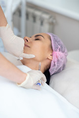 Woman having injection in neck while having anti-aging procedures