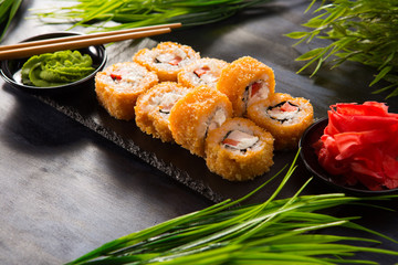 Set of fried sushi rolls with wasabi and ginger on a black background. Japanese oriental cuisine