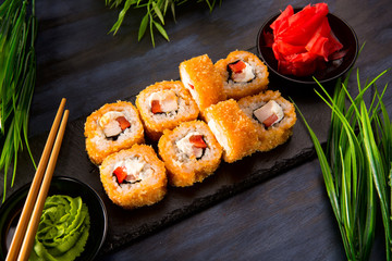 Set of fried sushi rolls with wasabi and ginger on a black background. Japanese oriental cuisine