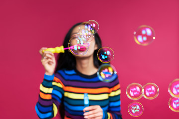 Happy beautiful woman blowing soap bubbles