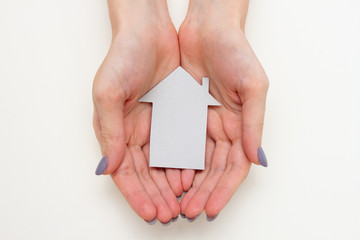 cardboard sign of a house in female hands on a white background