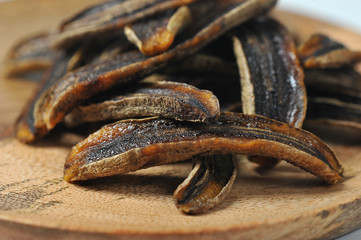 Sun-dried bananas on a wooden surface.  Bananas occupy the entire frame space.  Macro shot.