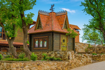 Beautiful wooden house with weather vane and red tiles in a green garden