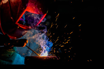 A craftman is welding with workpiece steel.Working person About welder steel Using electric welding machine There are lines of light coming out and safety equipment in factory industry.