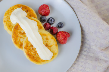 Pancakes with sour cream frozen blueberries and raspberries.