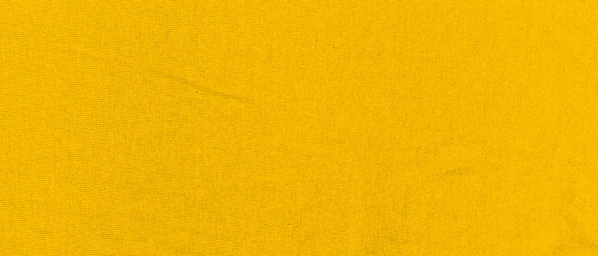 Vibrant yellow texture of binding fabric. Yellow textile background with natural folds. Close-up