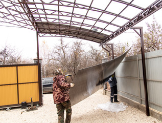 A worker mounts a metal canopy