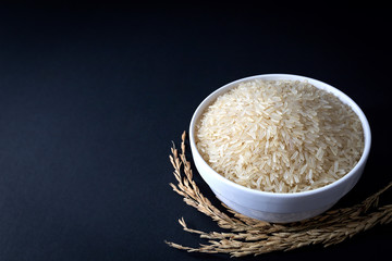 Thai parboiled rice in white ceramic bowl on black background. 45 degree angle. close up shot.