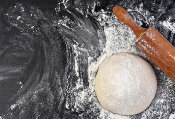 Preparation of the dough. The rolling pin with flour on a dark background