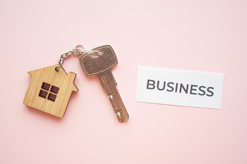 Wooden house toy and silver key on bright pink background with phrase quote business. Mortgage, house buy sell, investment, rent, realtor concept