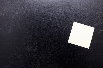 Stationery yellow stickers for inscription on a black leather isolated background. Blank sticker...