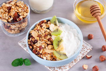 Granola with Greek yogurt kiwi and banana in a bowl with a spoon.