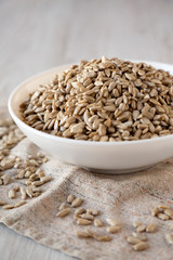 Raw Sunflower Seed Kernels in a white bowl on a white wooden background, low angle view. Close-up.