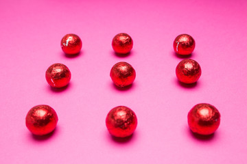 Chocolates in a multi-colored foil on a pink background
