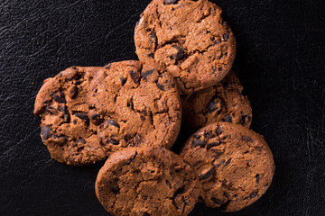 Appetizing chocolate chip cookies with slices of raisins on a black background.