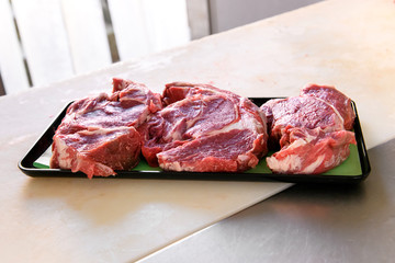 Tray of freshly cut raw chuck steaks on a counter
