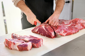 Butcher or cook slicing chuck steaks
