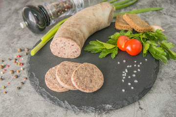 Sliced liver pate, on black slate with herbs and spices. Side view.