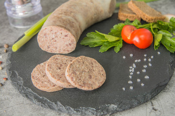 Sliced liver pate, on black slate with herbs and spices. Close-up.