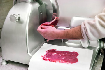 Butcher using a circular blade to slice beef