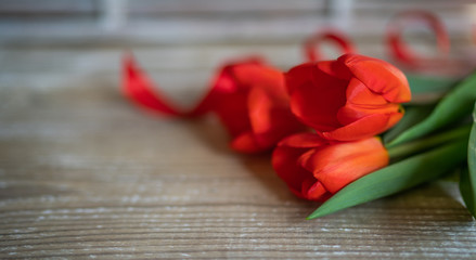 Fresh spring red tulips flowers on shabby rustic table wooden planks. Selective focus. Place for text. Toned image.