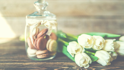 Fototapeta na wymiar Spring flowers. Bouquet of white tulips and macaroons on brown wooden table. Mother's Day and Valentines Day background. Rustic style. Copy space for your text.