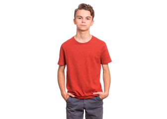 Fototapeta premium Handsome happy teen boy with hands in pockets, isolated on white background. Photo of adorable young smiling child looking at camera, front view. Emotional portrait of caucasian teenager.