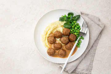 meatballs with mashed potato, cream sauce and green peas on white plate