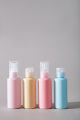 Travel kit. Set of four plastic bottles for cosmetic products. Gray background