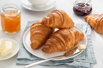 freshly baked croissants with jam and butter for breakfast