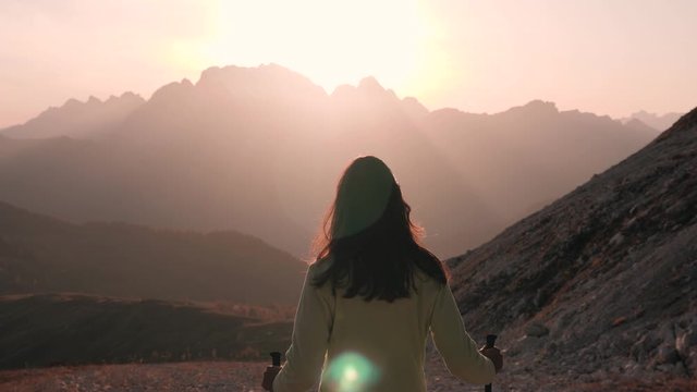 A woman traveler hiking down a mountain trail at sunrise in the Dolomites in Italy SLOW MOTION.