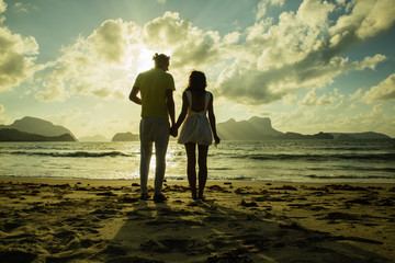 young couple on the sunset time at the beach holding their hands