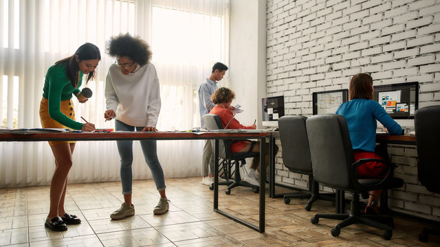 Creative team. Group of young multicultural people working and discussing fresh ideas in the modern office. Web designers in casual wear working together - Powered by Adobe