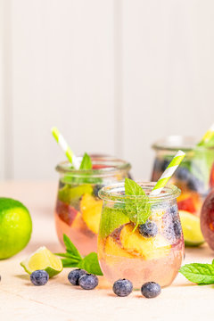 Blueberry and peach infused water, cocktail, lemonade or tea in jar with water drops. Summer iced cold drink with blueberry, lime, peach and mint