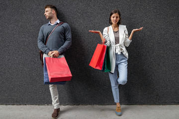 Woman and man holding shopping bags having conflict about money