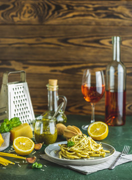 Gray plate of spaghetti pasta bucatini with pesto sauce and parmesan. Italian traditional perciatelli pasta by genovese pesto sauce served with wine