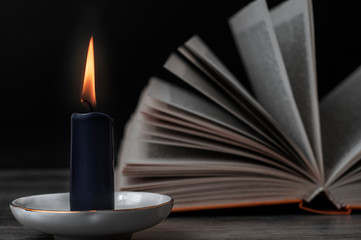 A burning candle and an open book. Set for witches.