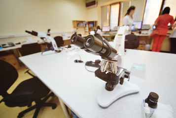 a medic or scientist examines bacteria in a microscope against the backdrop of a bacteriological laboratory